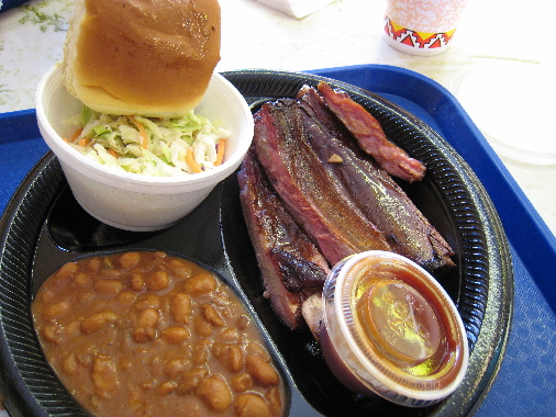 An order of ribs and two sides: coleslaw and spicy beans.