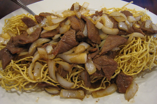 A gigantic platter of noodles, grilled beef and onion