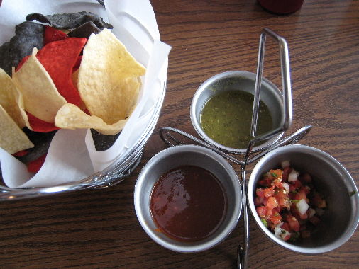 Three salsas with red, yellow and blue corn chips